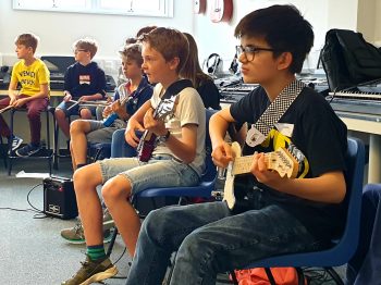 Children learning guitar and drumming